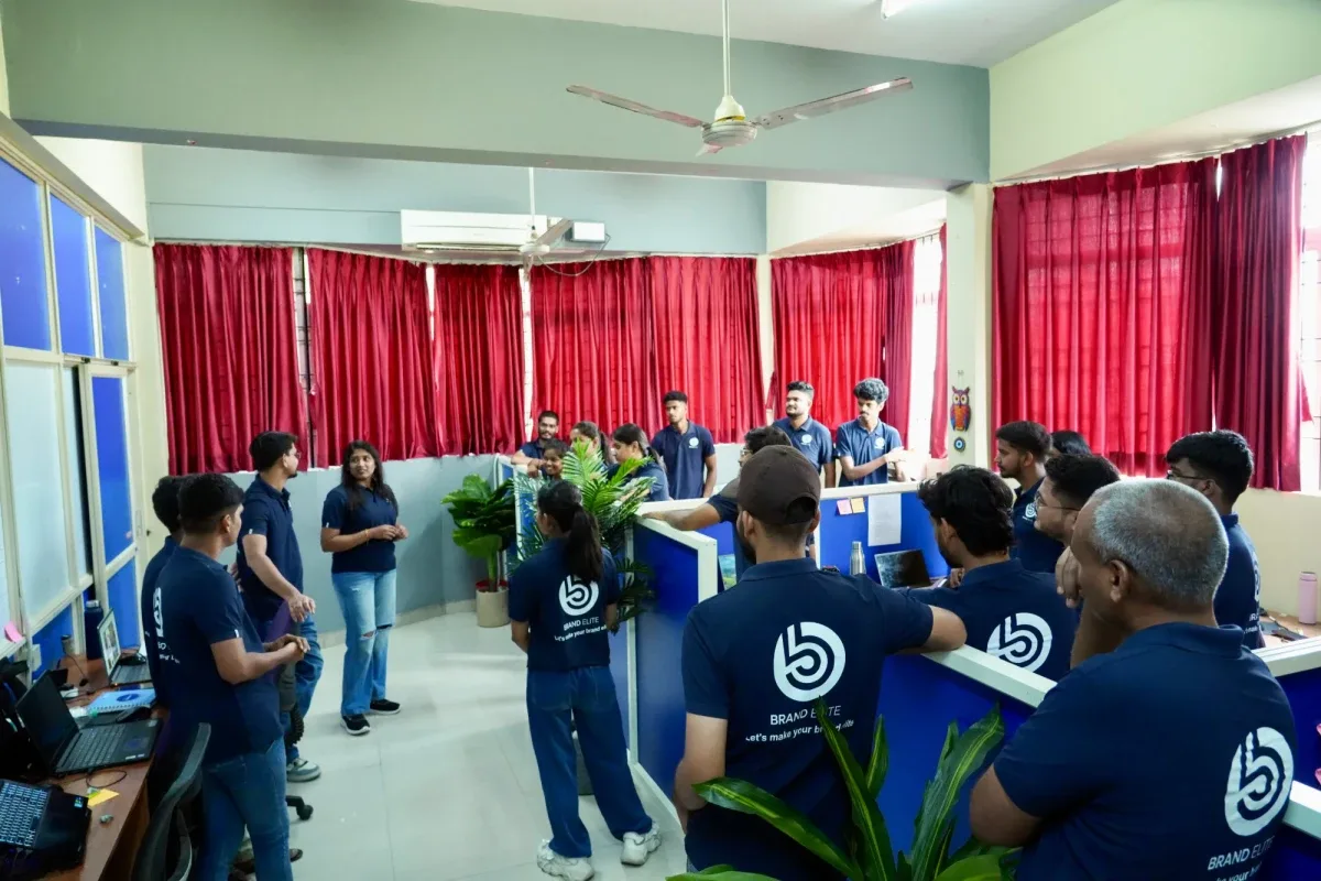 Team members listening during a meeting between the desks in the Brand Elite office